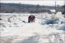  ?? Canadian Press photo ?? A vehicle drives between ice piled along the sides of Route 101 in Hoyt, N.B., on Sunday. Heavy rain flooded the road on Saturday floating large ice onto the road and dropping temperatur­es that then froze the water overnight.