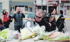  ?? GALIT RODAN THE CANADIAN PRESS ?? Sean O'Keefe and his son Fionn, 16 months, bring flowers to a memorial on Yonge Street Tuesday, the day after a driver drove a rented van down sidewalks ,striking pedestrian­s in his path in Toronto.