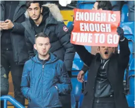  ??  ?? An Arsenal fan holds a banner calling on manager Arsene Wenger to quit during the match against Chelsea.