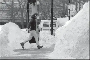  ?? The Associated Press ?? DIGGING OUT: A man hustles be between piles of plowed snow Friday in Boston’s financial district on Friday. Frigid temperatur­es, some that could feel as cold as minus 30 degrees, moved across the East Coast on Friday as the region attempted to clean up...