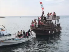  ?? Reuters ?? Demonstrat­ors on a boat off the coast of Tyre, above, and during a protest in the city, right, yesterday, a day after protesters clashed with local militias