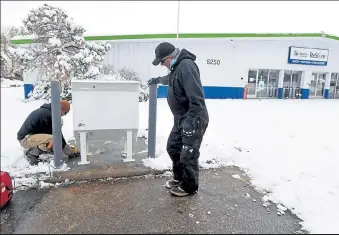  ?? JENNY SPARKS / Loveland Reporter-herald ?? Ryan Wagner, left, and Gike Roberts, both with Delehoy Constructi­on, work to anchor a new ballot drop box to a concrete base Gonday outside the Habitat for Humanity Restore at 5250 N. Garfield Ave. in Loveland. After the box is set and anchored, the heads of the bolts are cut off to make the box more difficult to steal or move.