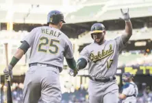  ?? Stephen Brashear / Getty Images ?? Chris Smith, at 36 the oldest A’s pitcher ever to make his first big-league start, delivers a pitch during the first inning. Yonder Alonso is congratula­ted by Ryon Healy — who drove in the winning run — after hitting a homer in the third inning.