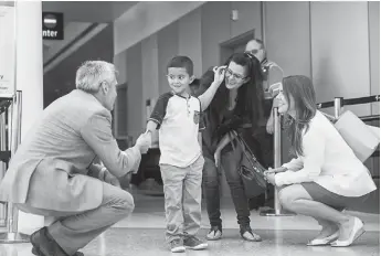  ?? Associated Press ?? ■ Jelsin Aguilar Padilla shakes immigratio­n attorney Jorge L. Baron’s hand Saturday after stepping off his flight from New York into the Seattle-Tacoma Internatio­nal Airport as he is reunited with his mother, Yolany, in Seattle. A federal judge on Monday ordered a temporary halt to deportatio­ns of immigrant families reunited after being separated at the border, as the Trump administra­tion races to meet a July 26 deadline for putting more than 2,500 children back in their parents’ arms.