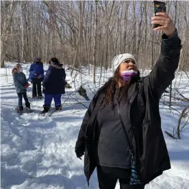  ??  ?? Bezhig Hunter, a fifth-grade teacher at Waadookoda­ading, holds her phone high so students who could not make the trip can participat­e virtually. Photograph: Mario Koran/The Guardian