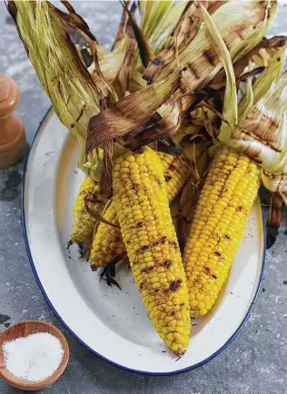  ?? John Kernick / Everyday Food ?? Gill whole ears of sweet corn with the husks on for about 20 minutes over medium heat. That will protect the corn from burning and keep it moist.