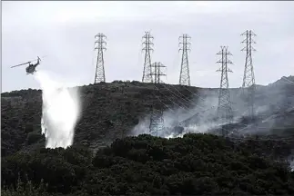  ?? JEFF CHIU / AP/ ?? In October, a helicopter drops water near power lines and electrical towers while working at a fire on San Bruno Mountain near Brisbane.