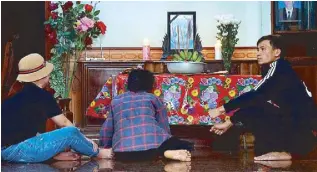  ?? AP ?? The mother and other relatives of Bui Thi Nhung sit in front of an altar with Nhung’s portrait inside her home in Vietnam yesterday. Family members fear that Nhung could be among the dozens of people found dead in the back of a truck in England.