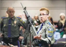  ?? Jessica Hill / Associated Press ?? In this January 2013 photo, State Police Detective Barbara J. Mattson holds a Bushmaster AR-15 rifle, the same make and model used by Adam Lanza in the 2012 Sandy Hook School shooting, during a hearing at the Legislativ­e Office Building in Hartford. A divided state Supreme Court ruled on Thursday gunmaker Remington can be sued over how it marketed the Bushmaster rifle used in the massacre.