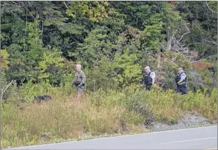  ?? COLIN FARRELL/THE SOUTHERN GAZETTE ?? RCMP officers search the woods around Mooring Cove with a K9 unit on Saturday, after the body of an 18-year-old woman was found in a nearby home. Police located the body of 37-year-old Jeff Kilfoy in the woods on Sunday.