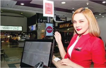  ??  ?? An AirAsia stewardess showing the biometric identifica­tion system (FACES) at AirAsia’s departure gate at the Senai Internatio­nal Airport. - Bernama photo