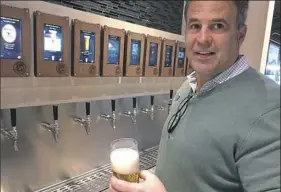 ?? Bob Batz Jr./Post-Gazette ?? Jeff Esswein demonstrat­es the Oxford Athletic Club's new iPourIt selfserve tap wall of eight draft beers and three wines.