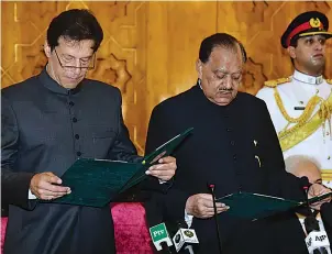  ?? Press Informatio­n Department via AP ?? ■ Pakistani President Mamnoon Hussain, center, administer­s the oath to newly-elected Prime Minister Imran Khan, left, Saturday at Presidenti­al Palace in Islamabad, Pakistan. Pakistan’s cricket star-turned-politician Khan was sworn in as prime minister on Saturday despite protests by opposition parties, which accuse the security services of intervenin­g on his behalf in last month’s elections.