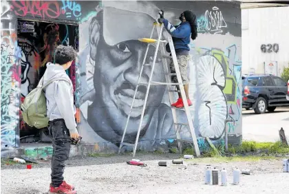  ?? Photo / AP ?? Johnathan Almendarez (left) watches as Theo Ponchaveli paints a mural of the likeness of Ahmaud Arbery in Dallas. Ponchaveli was inspired after seeing the video of Arbery’s death.