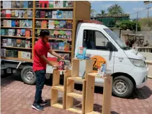  ??  ?? Ali al-Moussawi, the owner of a mobile book truck, arranges his books on a street in Baghdad. — AP
