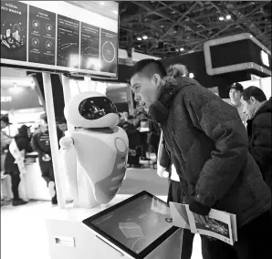  ?? CHEN XIAOGEN / FOR CHINA DAILY ?? An AI-supported robot addresses queries from a visitor at the China Finance Annual Forum held in Beijing on Thursday.