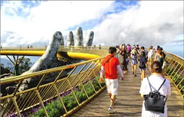  ??  ?? Visitors walk along the 150-metre long Cau Vang “Golden Bridge” in the Ba Na Hills near Danang. — AFP photos