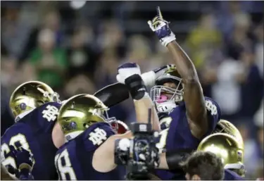  ?? CARLOS OSORIO — THE ASSOCIATED PRESS ?? Notre Dame running back Josh Adams points skyward while lifted by teammates after one of his three touchdowns in an NCAA college football game against Southern California, Saturday in South Bend, Ind.