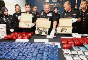  ??  ?? Major haul: Deputy Comm Roslee (centre) showing the seized drugs and pistols after the press conference at the state police headquarte­rs in George Town.