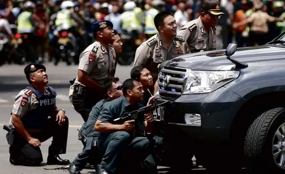  ?? REUTERS ?? ONTHE DEFENSIVE Indonesian police officers seek cover behind an SUV near a blast site in Jakarta on Thursday. Several explosions went off and gunfire broke out in the Indonesian capital that killed at least seven, including what police said was the suicide bomber behind one of the blasts.