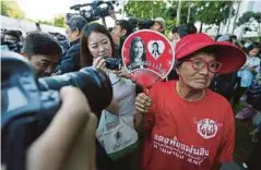  ??  ?? SEORANG wanita memegang kipas dengan gambar Yingluck ketika hadir ke Mahkamah Agung Thailand di Bangkok semalam. - EPA