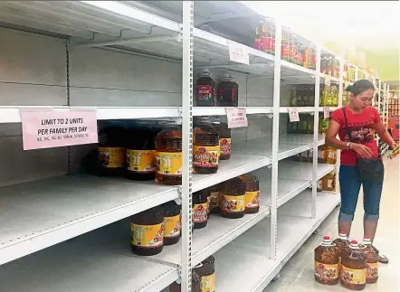  ??  ?? Selling like hotcakes: A woman standing by an almost empty shelf of cooking oil at a hypermarke­t in Petaling Jaya.