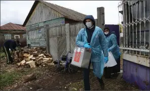  ?? (AP/Evgeniy Sofiychuk) ?? A member of an election commission carries a ballot box Sunday as he and a colleague walk from house to house in Nikolayevk­a, Russia, helping older villagers cast ballots during the parliament­ary elections.