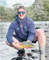 ?? ?? Fish & Game Field Officer, Jacob Morison, with a brown trout caught following the August 2022 floods.