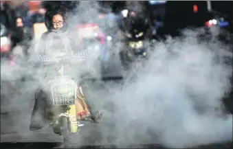  ?? WU JUNJIE / CHINA NEWS SERVICE ?? A mist of water vapor clouds a street in Taiyuan, Shanxi province, on Wednesday. The steam rose from the city’s heating pipeline system and cooled due to the low surface temperatur­e. A cold front was forecast to send temperatur­es falling by up to 10...