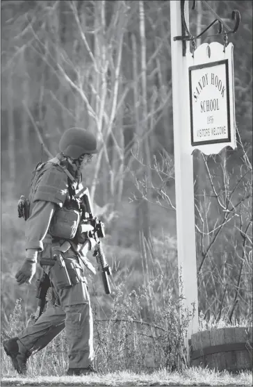  ?? Don Emmert/afp/getty Images ?? A heavily armed state trooper leaves Sandy Hook Elementary School in Newtown, Conn., on Friday. A gunman slaughtere­d 20 youngsters and six teachers before turning one of his weapons on himself.