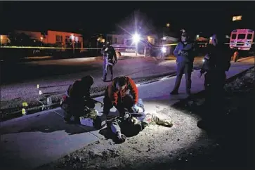  ?? Gary Coronado Los Angeles Times ?? PARAMEDICS and police in Tijuana attend to a man shot dead in December. In Tijuana, where gangs have been battling over a lucrative drug market, a report found there were about seven killings on average per day.