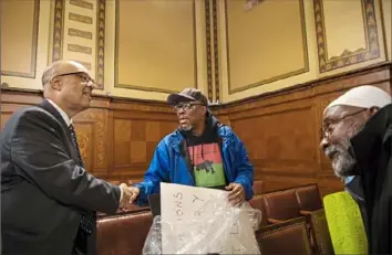  ?? Jessie Wardarski/Post-Gazette ?? District 9 Councilman the Rev. Ricky Burgess, left, speaks to community activist Khalid Raheem, of Manchester, center, and Yusef Ali, of the West End, after a hearing on reparation­s Wednesday at the City County Building, Downtown.