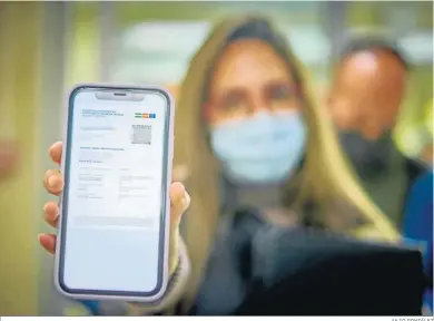  ?? JULIO GONZÁLEZ ?? Una chica mostrando ayer su pasaporte Covid en la pantalla de su móvil a la entrada del Puerta del Mar.