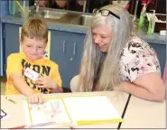  ?? PHOTO BY JESSICA MURRAY/ULSTER BOCES COMMUNITY RELATIONS ?? Reilly McGahan, a kindergart­en student in Jessica Compain’sclass at Highland Elementary School, shows Holly Brooker, a Highland Rotarian andJunior Achievemen­t volunteer, a drawing depicting how he could earn money.