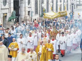  ?? FOTO: MATTHIAS BALK ?? Gläubige ziehen in einer Fronleichn­amsprozess­ion durch die Münchner Innenstadt. Nach zwei Jahren Einschränk­ungen durch die Corona-Pandemie kann das katholisch­e Fest dieses Jahr wieder gefeiert werden.