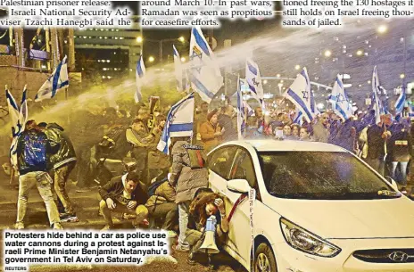  ?? REUTERS ?? Protesters hide behind a car as police use water cannons during a protest against Israeli Prime Minister Benjamin Netanyahu’s government in Tel Aviv on Saturday.