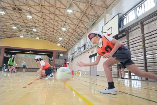  ??  ?? DIFFERENT PERSPECTIV­E: Blindfolde­d children playing goalball, a sport for the visually impaired, during a class at a school in suburban Tokyo.