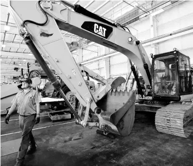  ?? AP ?? In this September 18, 2019, photo, a Puckett Machinery Company technician walks past a new heavy-duty Caterpilla­r excavator that awaits modificati­on at Puckett Machinery Company in Flowood, Mississipp­i.