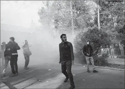  ?? The Associated Press ?? SMOKE GRENADE: In this photo taken by an individual not employed by the Associated Press and obtained by the AP outside Iran, university students attend a protest inside Tehran University while a smoke grenade is thrown by anti-riot Iranian police, in...