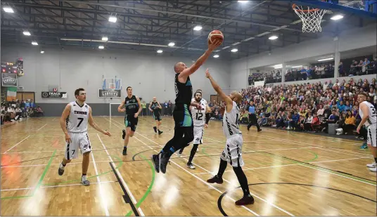  ??  ?? Kieran Donaghy scores a basket for Tralee Warriors as Isaac Westbrook, Swords Thunder, attempts to block him during Saturday’s Superleagu­e game in front of another packed house and on the new floor at Tralee Sports Complex. Photo by Domnick Walsh