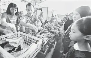  ?? — Gambar Bernama ?? PERCUMA: Ahmad Fahmi (dua kiri) menyusun sayuran yang diberikan secara percuma kepada penduduk setempat melalui Kechara Soup Kitchen (KSK) pada program My Community Care 2018 di Dataran Seri Angkasa, Kuala Lumpur semalam.
