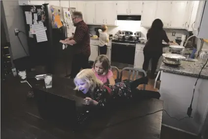  ?? ASSOCIATED PRESS ?? JESSICA AND JOHN FRANZ PREPARE THANKSGIVI­NG DINNER while their daughters Quinn, 2, and Molly, 8, talk on a Zoom call with family members Thursday in Olathe, Kan. Also in background middle, is daughter Amelia, 11. The family was having a quiet scaled-back Thanksgivi­ng with just their household due to concerns about the coronaviru­s.