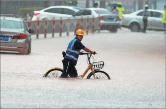  ?? CHEN LIJIE / FOR CHINA DAILY ?? A worker passes through a flooded street in Xiamen, Fujian province, on Wednesday. Rain in the city brought flooding and inconvenie­nce to the public.