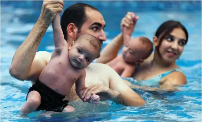  ??  ?? EGYPTIAN PARENTS teach their infants how to swim in a first-of-its-kind school in Cairo in August.