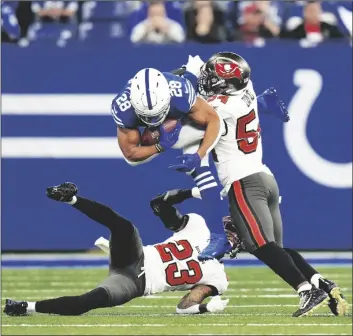  ?? AP PHOTO/AJ MAST ?? Indianapol­is Colts’ Jonathan Taylor (28) is tackled by Tampa Bay Buccaneers’ Sean Murphy-Bunting (23) and Lavonte David (54) during the first half of an NFL football game on Sunday in Indianapol­is.