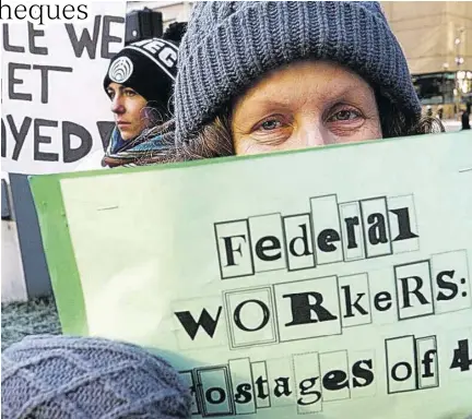  ?? (Photos: AP) ?? Esther Anastasia holds a sign during a protest rally with government workers and their supporters in Boston, on Friday.