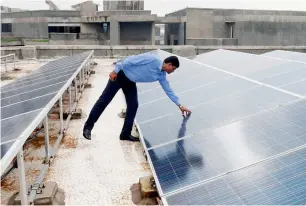  ?? AFP ?? Chinmay Ghoroi, associate professor at the Indian Institute of Technology Gandhinaga­r, next to roof-top solar panels at the IIT building in Gandhinaga­r, some 30km from Ahmedabad. —