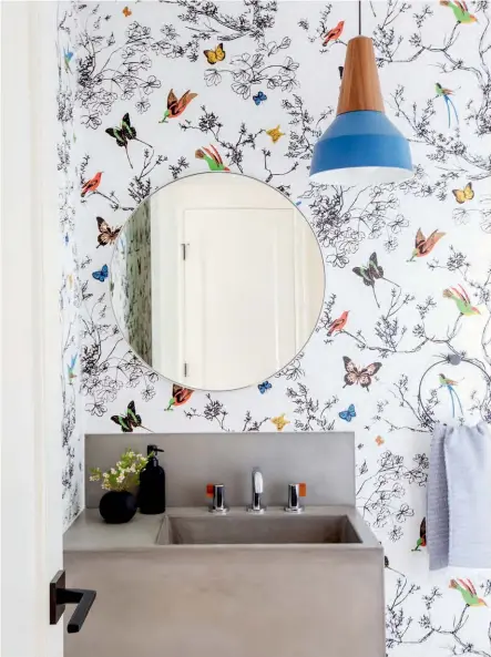  ??  ?? ABOVE In the powder room (which was reposition­ed to improve flow in the kitchen), whimsical bird and butterfly wallpaper is paired with a bold, utilitaria­n concrete sink in an irreverent design move that bucks tradition in this fresh, youthful home. A cleanlined mirror and accessorie­s reiterate the home’s contempora­ry tone.
Schumacher WALLPAPER, AnneStarr; PENDANT, Schneid; Kohler SINK, Brizo TAPS AND FAUCET, Robinson; VANITY, Concrete, Diamond Finishings.