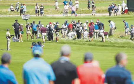  ?? Streeter Lecka, Getty Images ?? Dozens of people — from camera operators to course officials — help Dustin Johnson search for his ball in the rough alongside the fairway of the sixth hole during the first round of the U.S. Open at Shinnecock Hills in Southampto­n, N.Y.