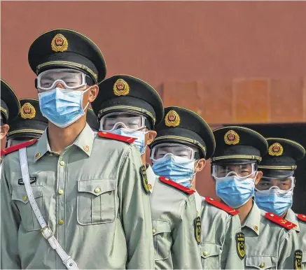  ?? PHOTO: GETTY ?? War of words: Chinese paramilita­ry police wear protective masks as they guard the entrance to the Forbidden City in Beijing.